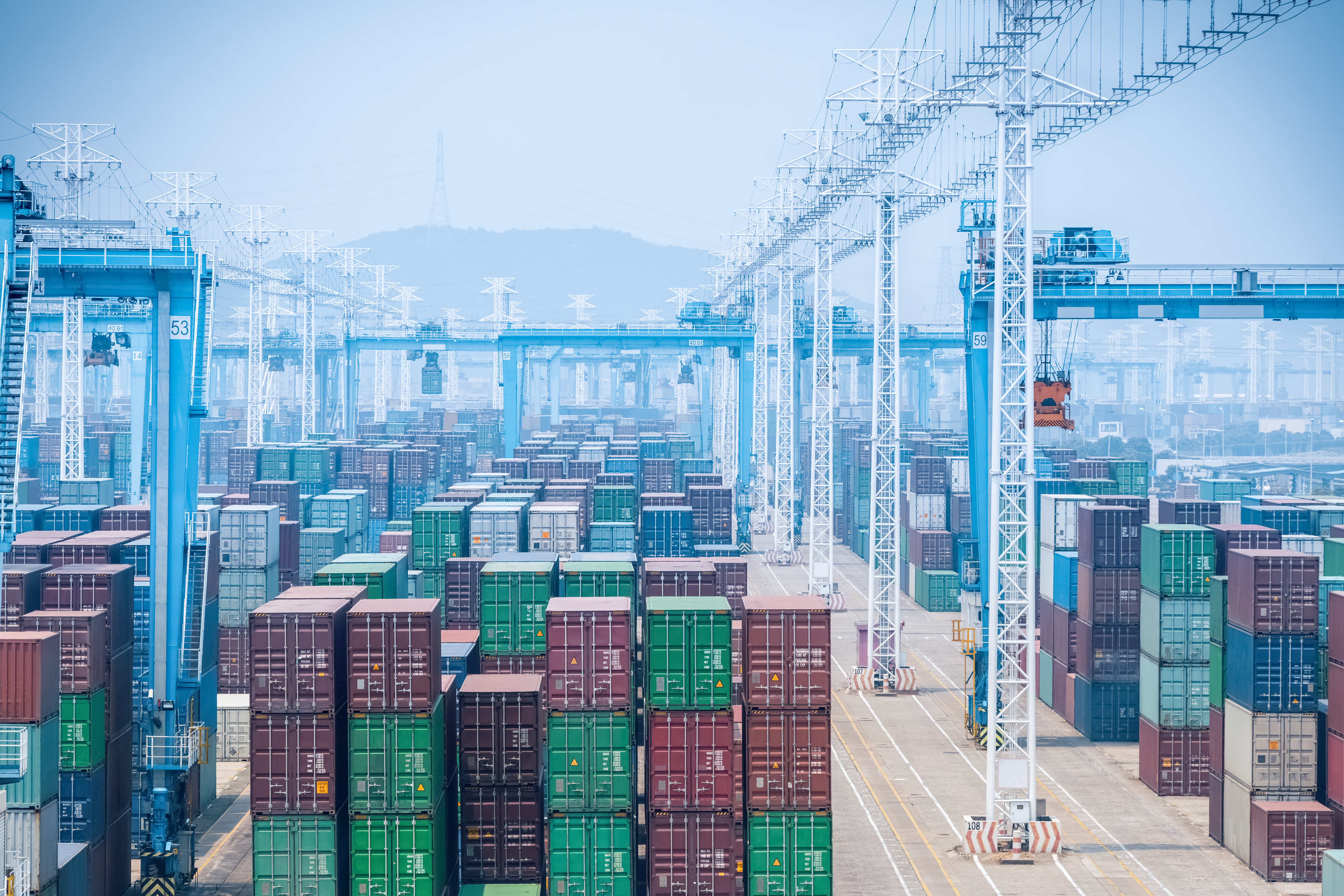 Large shipping container yard with blue cranes