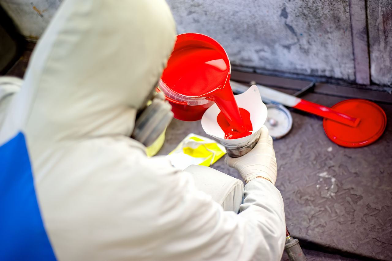 Worker pouring bright red pain in industrial setting