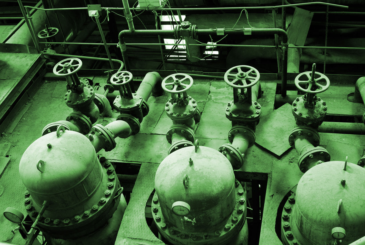 Industrial valves and pipes in green tinted facility