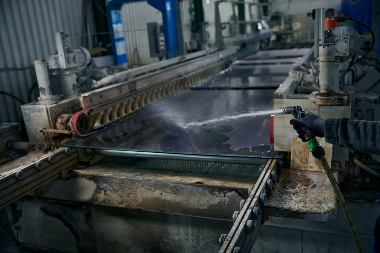 Industrial worker cleaning large metal machine surface