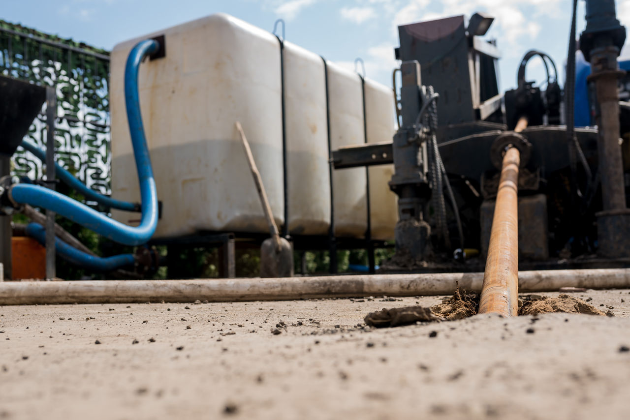 Agriculture farm pump in use with a big white tank and blue hose.