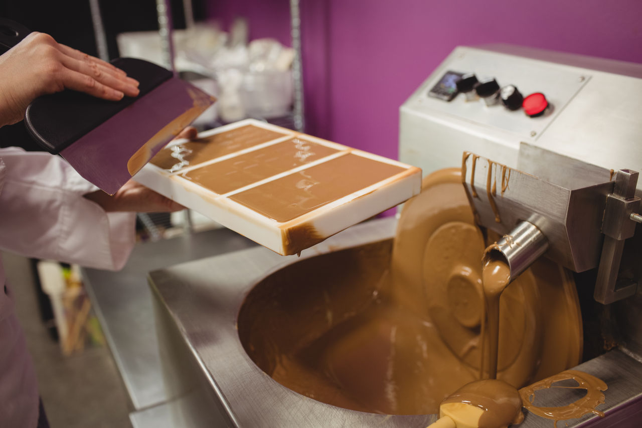 Person pouring melted chocolate into mold