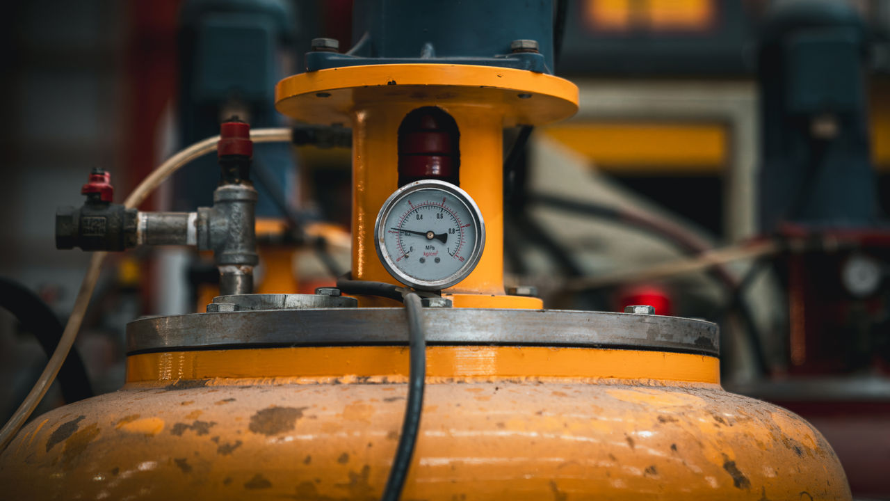 Industrial pressure gauge on yellow metal tank
