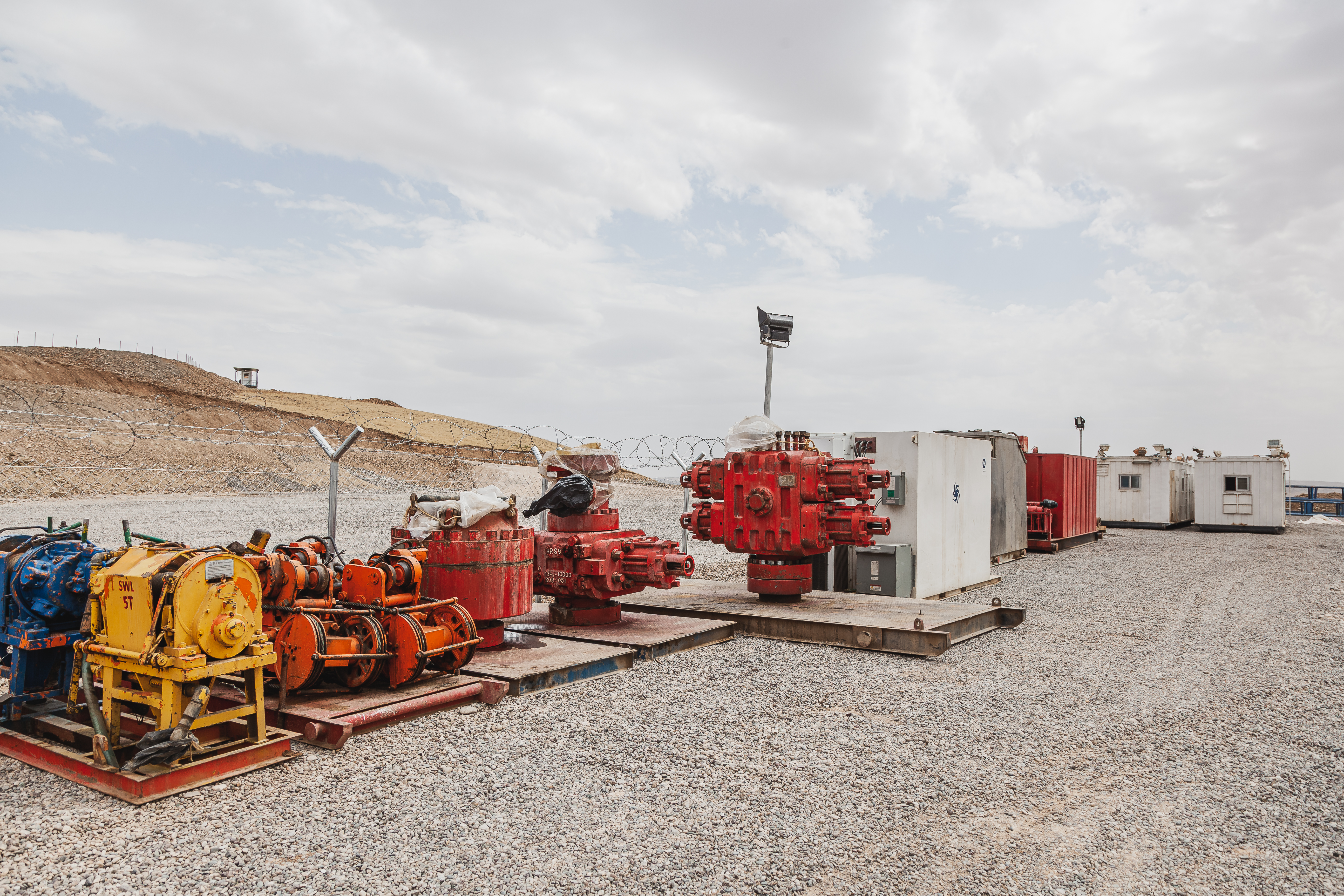 Industrial oilfield equipment on gravel worksite outdoors